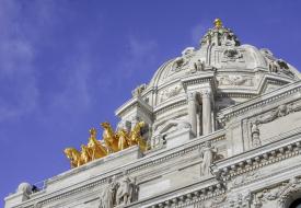 angled photo of the top of the capitol rotunda with gold horse statues