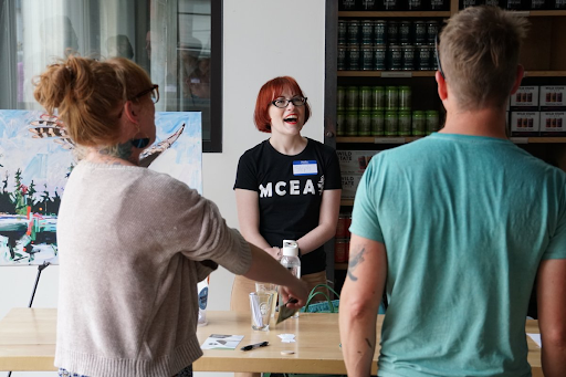 photo of MCEA staff member with red hair smiling and serving beers to people