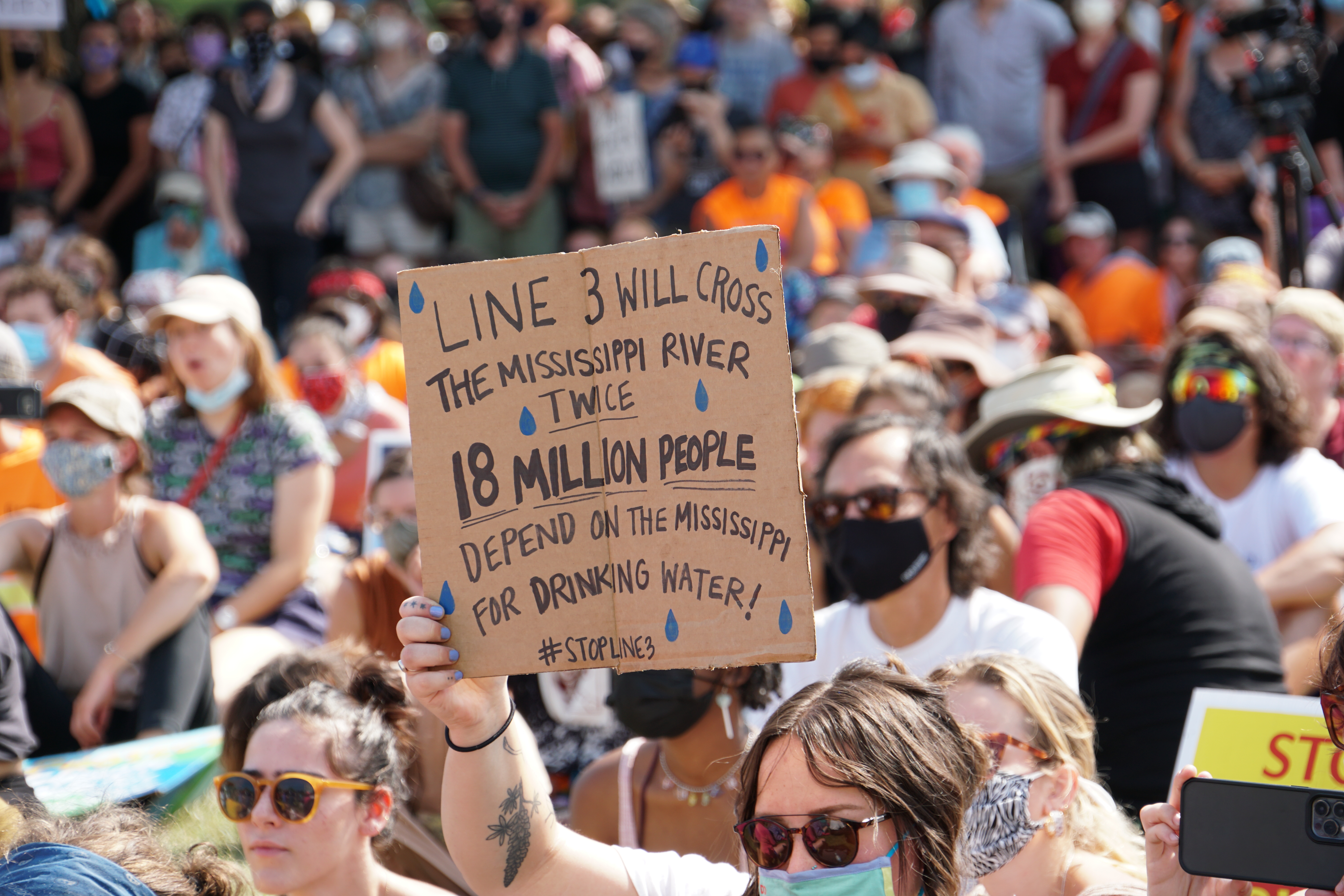 Image: protester holding a sign "line 2 will cross the Mississippi River TWICE 18 Million People depend on the Mississippi for drinking water! Stop Line 3