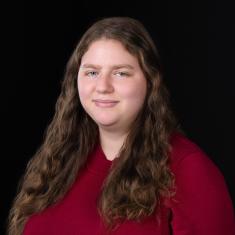 photo of evvie halpert, a white woman with long brown hair wearing a red shirt