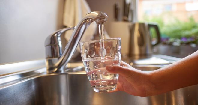 image of person filling water glass at a sink