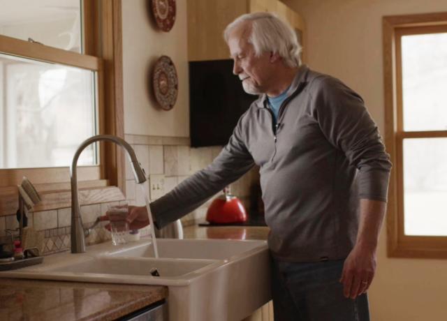 a white man getting some water from his kitchen tap