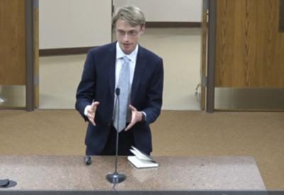 a young white man in a suit testifies in a suit