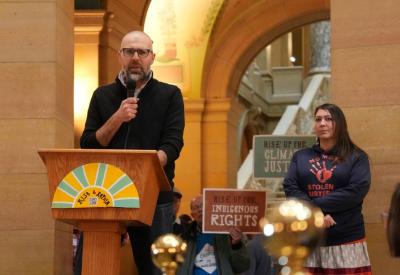 evan, a white man, stands giving a speech with indigenous activists at the capitol building 
