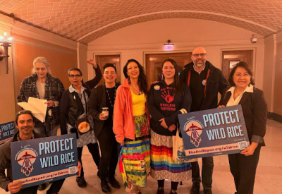 a group of people holding up signs to protect wild rice at minnesota capitol