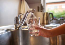 image of person filling a glass of water at the sink