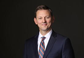 smiling white man with a red and blue on a dark background