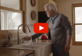 image of person filling a glass of water with video play button