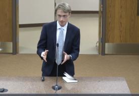 a young white man in a suit testifies in a suit