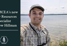 a photo of a white man in a hat smiling in front of a lake