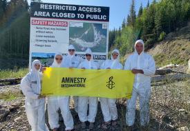 Amnesty International members outside of the Mount Polley disaster wearing hazmat suits