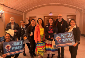 a group of people holding up signs to protect wild rice at minnesota capitol