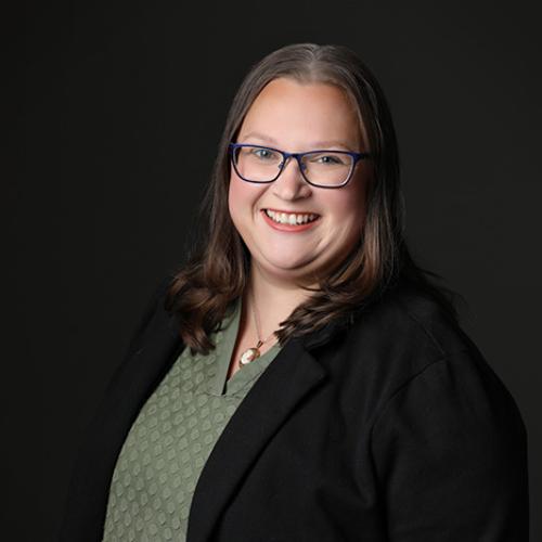 a photo of Andrea Lovoll, a white woman smiling in a green shirt and black blazer 