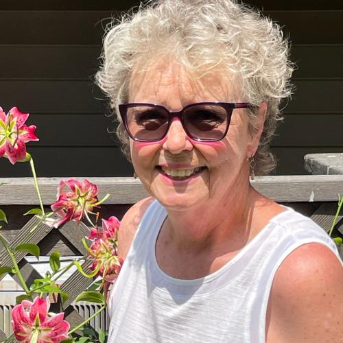 photo of cathy a women with white curly hair, smiling in sunglasses