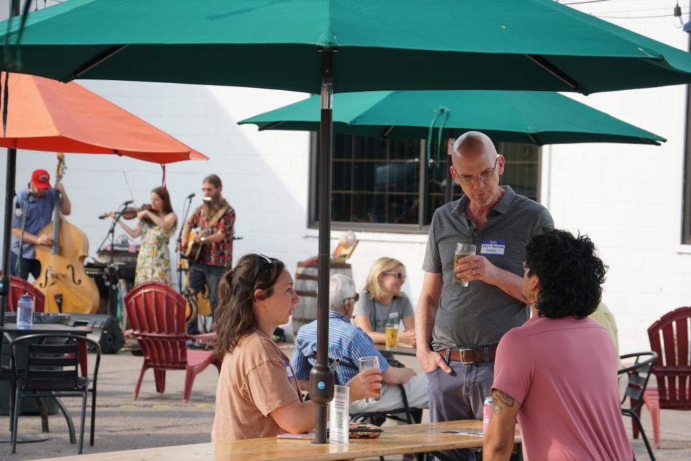 photo of M C E A staff member interacting with two supporters seated at a table