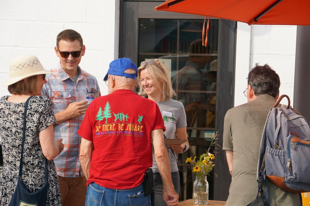 photo of two M C E A staff speaking with a group of supporters outside